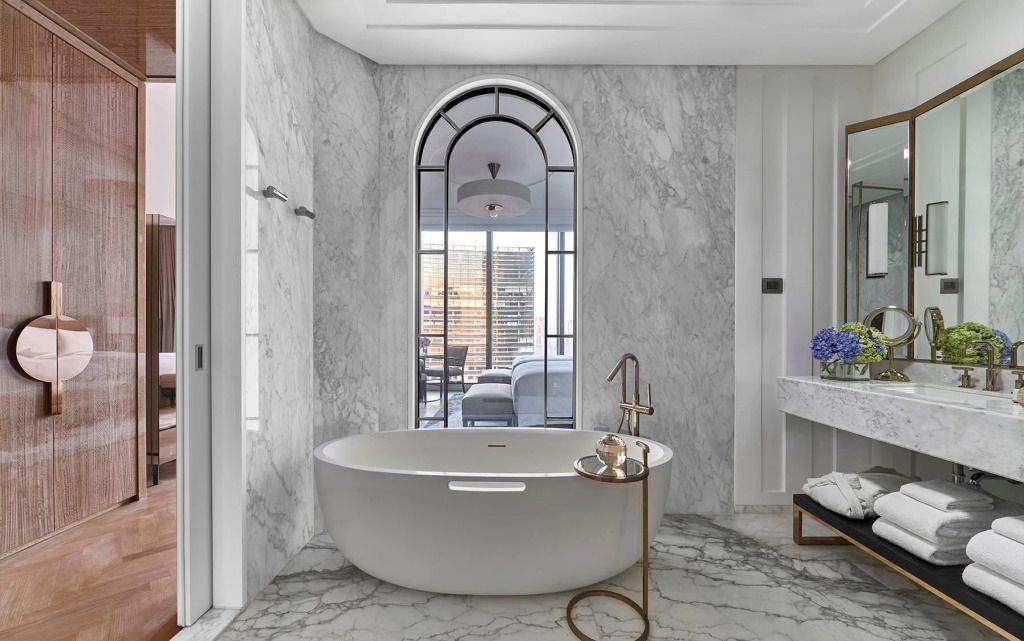 Luxuriöses Badezimmer mit freistehender Badewanne und großem Fenster im Langham Jakarta