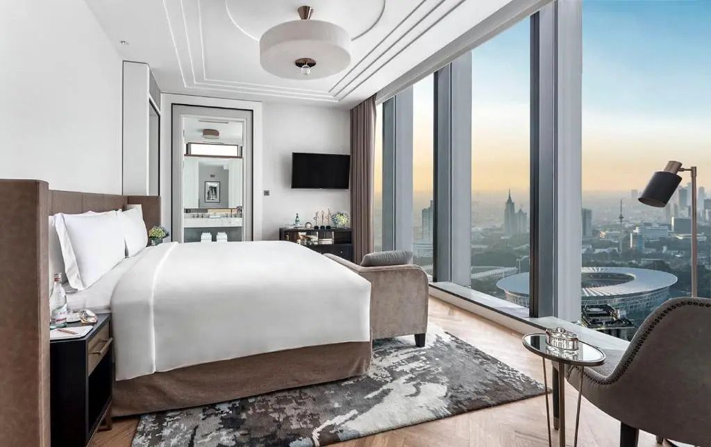 Modernes Doppelzimmer mit großem Fenster und Stadtblick bei Sonnenuntergang