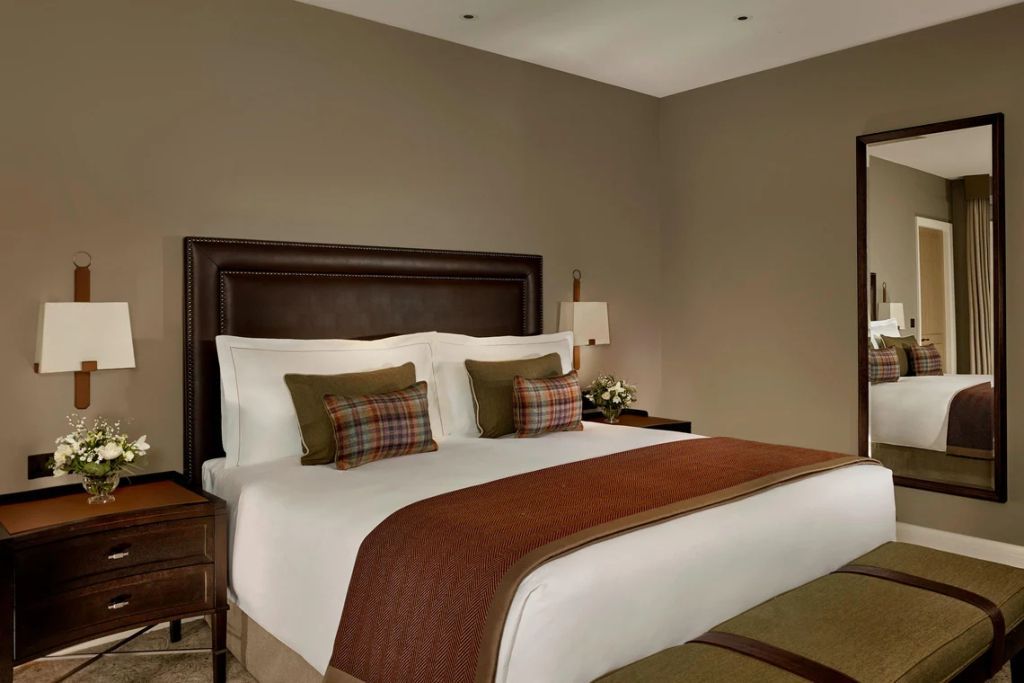 Elegantes Doppelbett in einem Deluxe Zimmer mit brauner Tagesdecke und dekorativen Kissen.