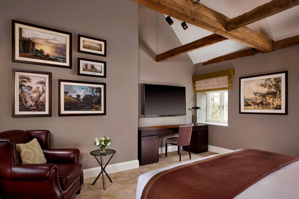 Stilvolles Zimmer mit Holzbalken, Schreibtisch und Wandkunst im Deluxe Zimmer.