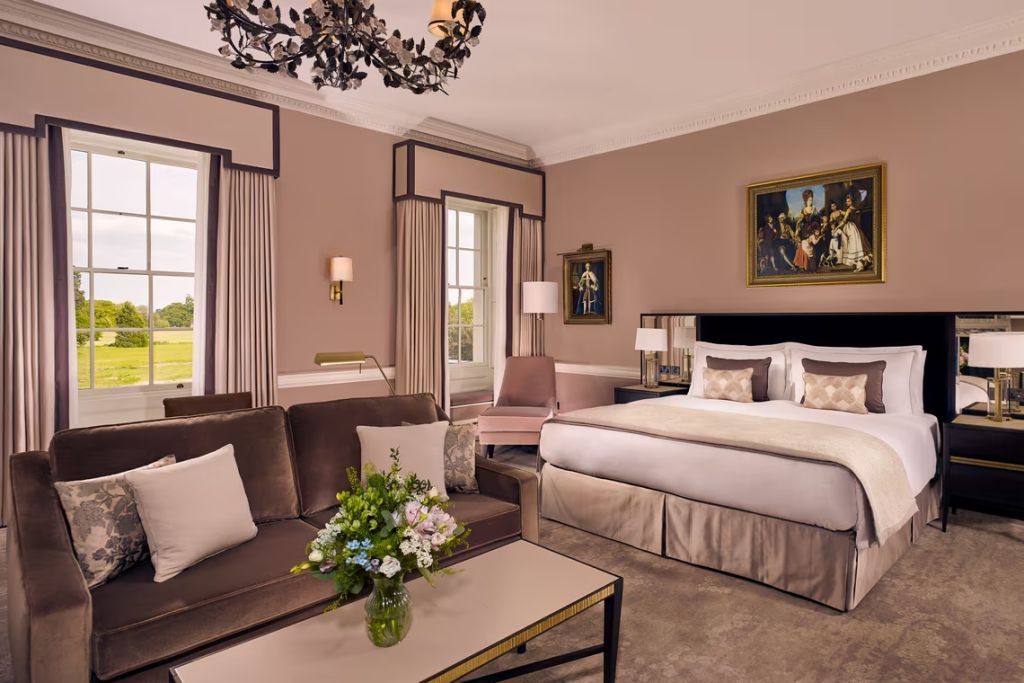 Elegantes Schlafzimmer mit Doppelbett und großen Fenstern zur grünen Landschaft.