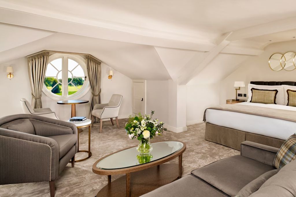 Helle Junior-Suite mit gemütlichem Sitzbereich. Großes Fenster mit Gartenblick.