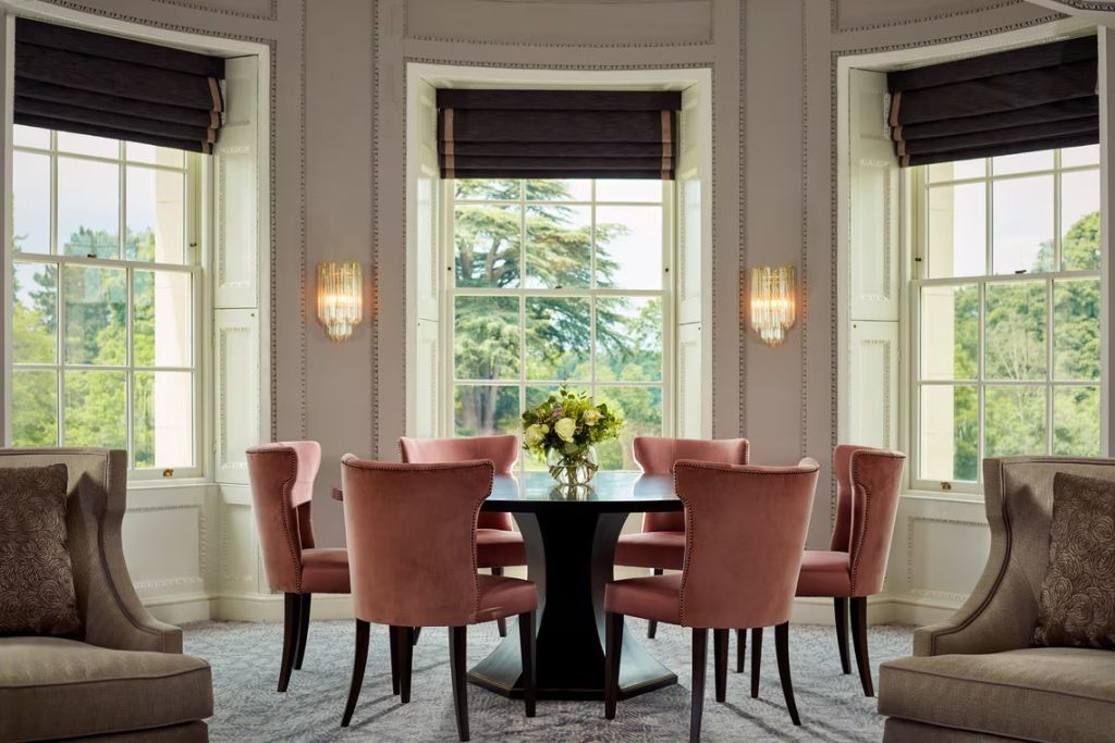Eleganter Essbereich mit großen Fenstern. Sitzmöbel in edlem Roséton.