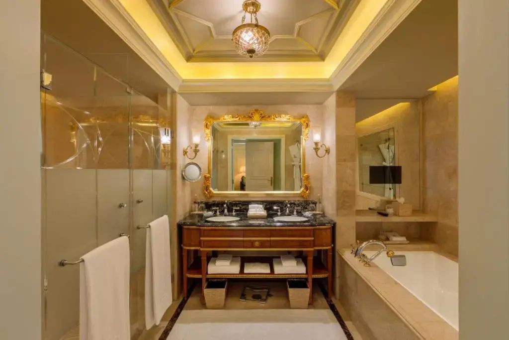 Luxuriöses Badezimmer mit goldenen Akzenten, Badewanne und großem Spiegel