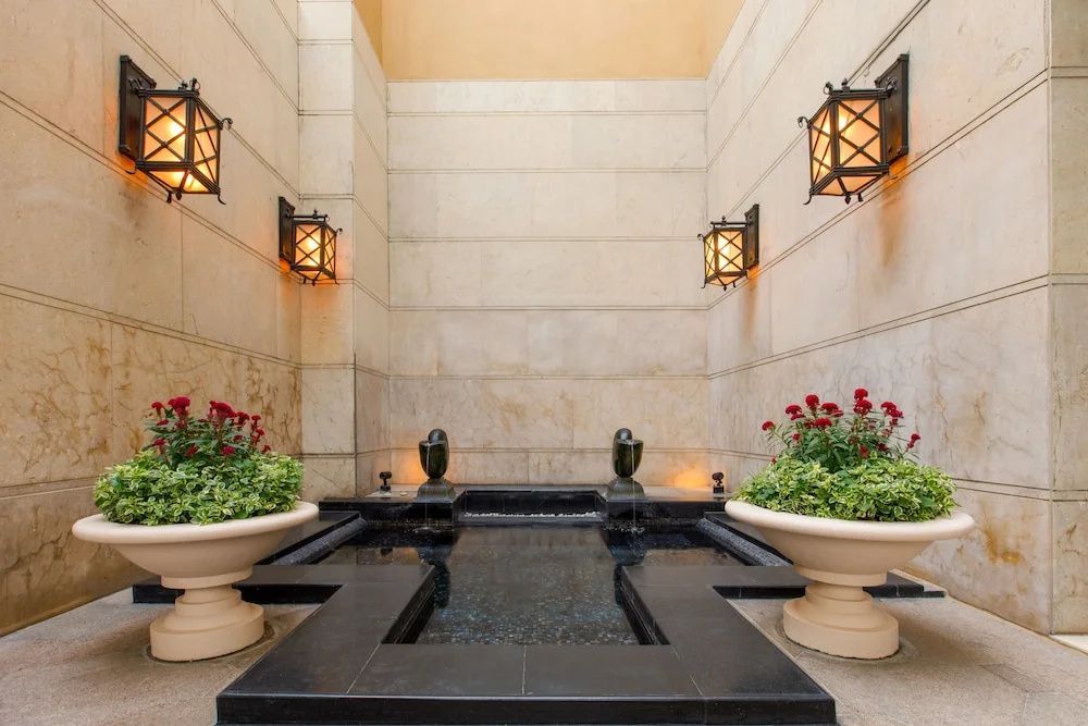 Eleganter Innenhof mit kleinem Wasserspiel und dekorativen Pflanzen in klassischen Töpfen