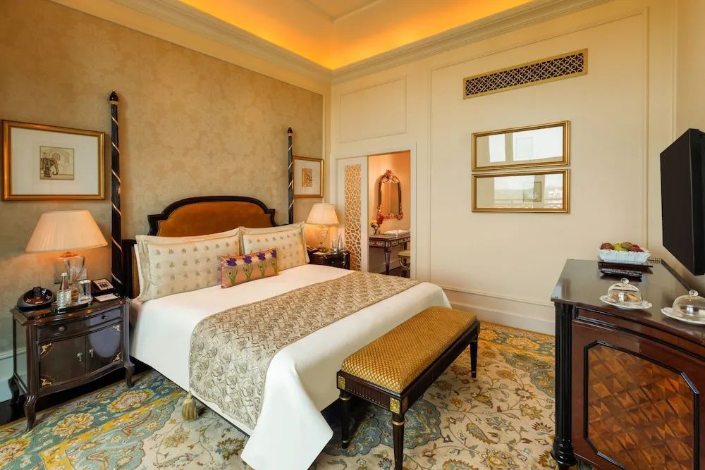 Luxuriöse Suite mit Doppelbett, stilvollem Teppich und eleganter Sitzbank in warmen Farbtönen