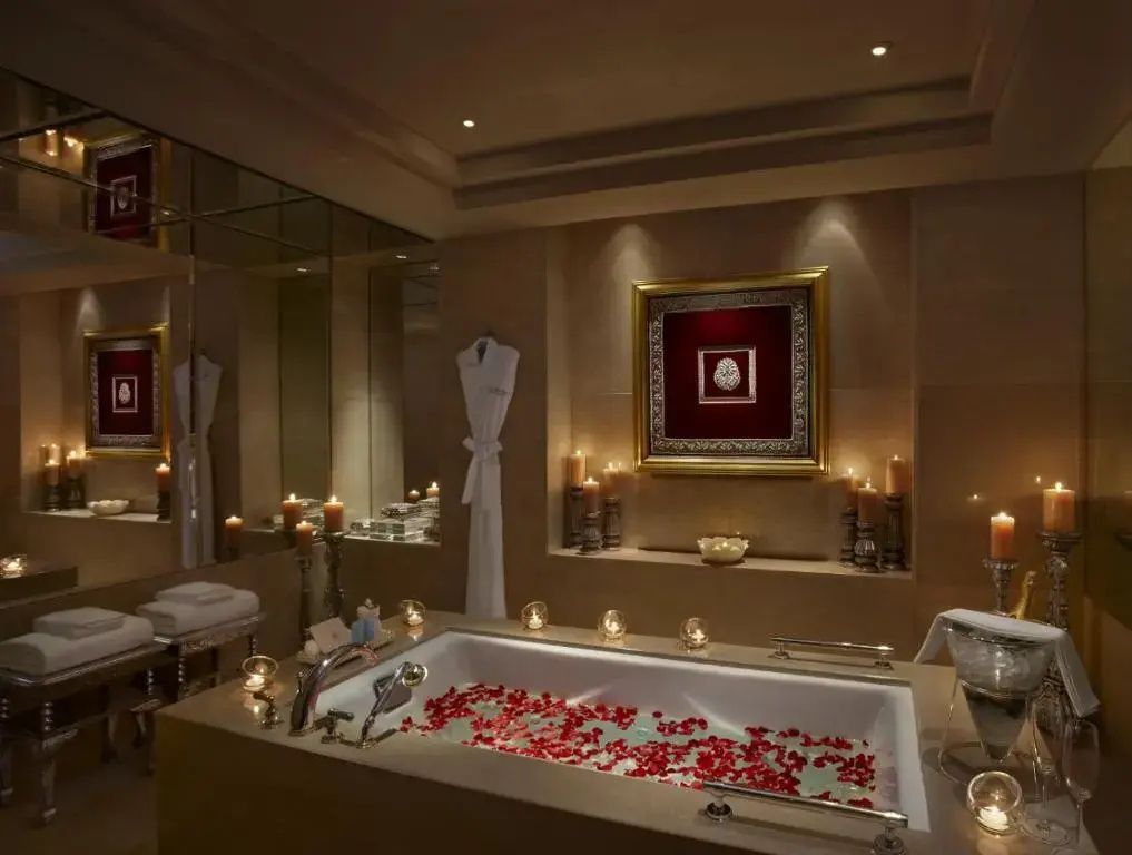 Luxuriöses Badezimmer mit großer Badewanne voller Rosenblüten.