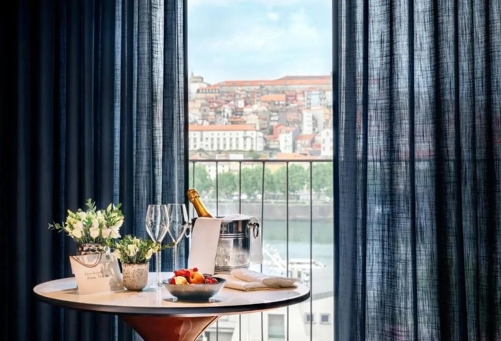 Deluxe-Zimmer mit Blick auf die Stadt und stilvoll gedecktem Tisch, Champagner und Früchte.