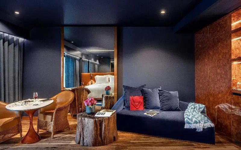 Hotelzimmer mit Sofa, dekorativen Kissen, Tisch und dunklen Wänden