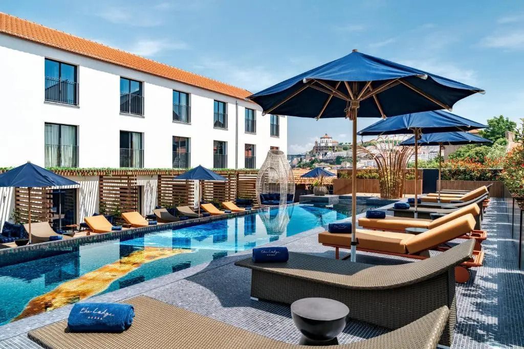 Moderner Poolbereich mit Liegen und Sonnenschirmen, umgeben von Hotelgebäuden.