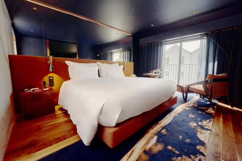 Elegantes Doppelzimmer mit großem Bett und Balkon.