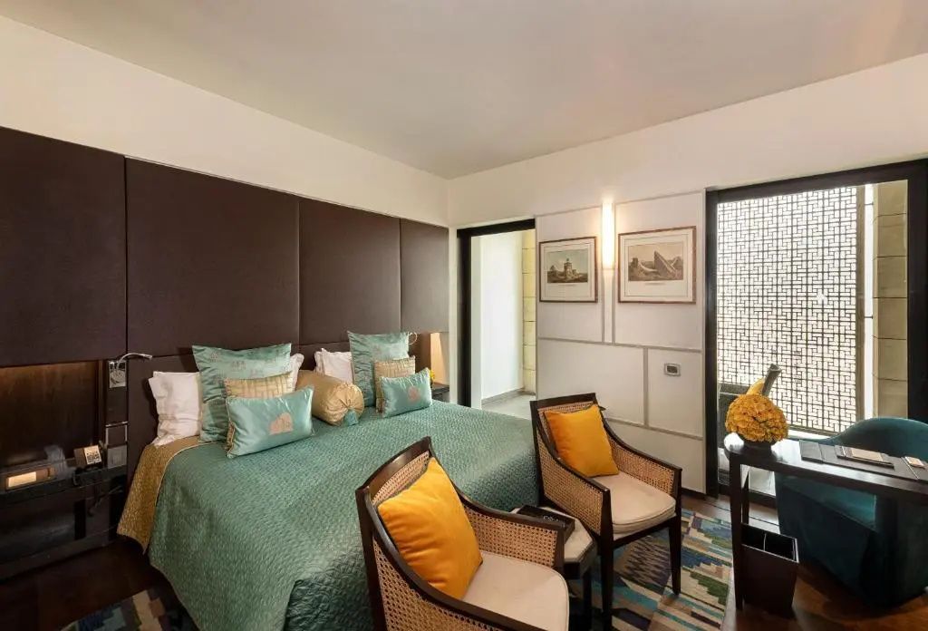 Lodhi Deluxe Suite mit Doppelbett, dekorativen Kissen und stilvollen Akzenten.