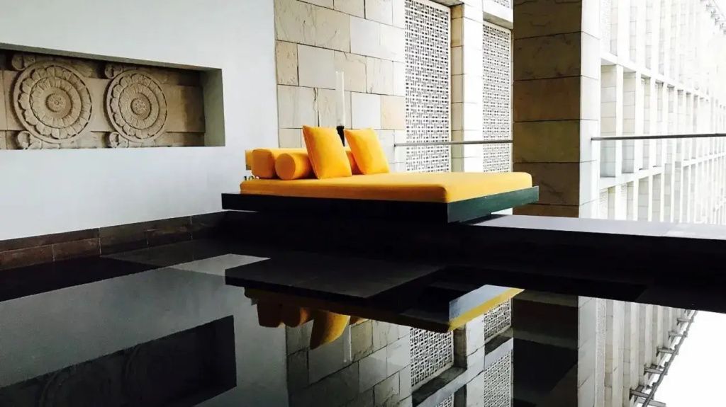 Elegantes Lounge-Bett in einem modernen Innenbereich mit Wasserreflexion.