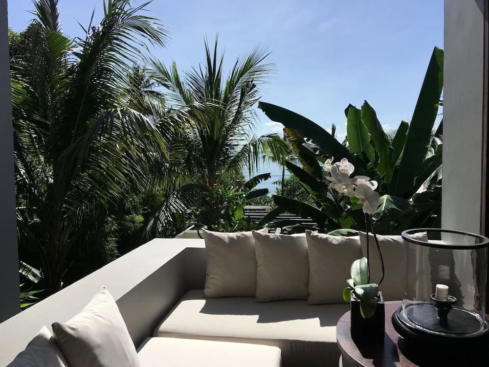 Sitzbereich auf der Terrasse mit Blick auf Palmen und Garten.