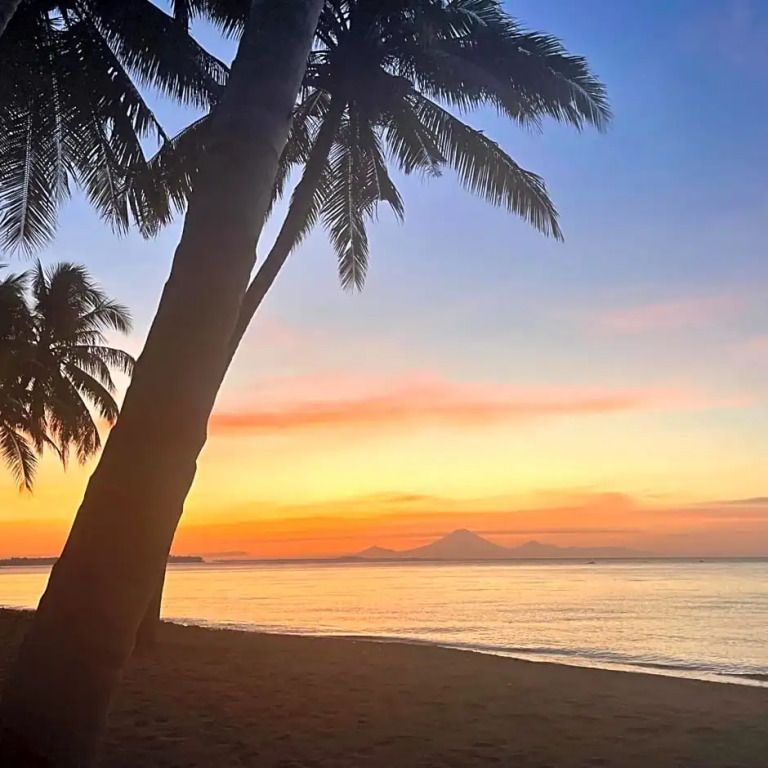 Sonnenuntergang am Strand mit Palmen und Vulkanblick
