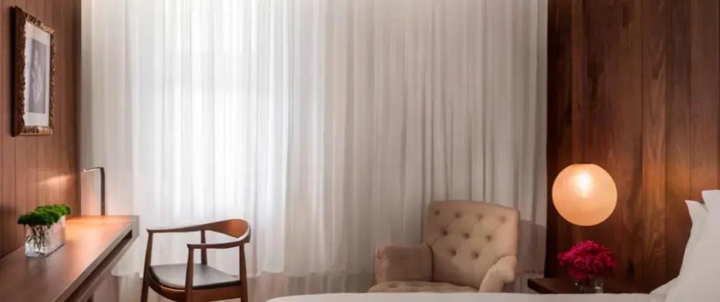 Heller Vorhang mit komfortablem Sessel und Holzstuhl in einem eleganten Ambiente