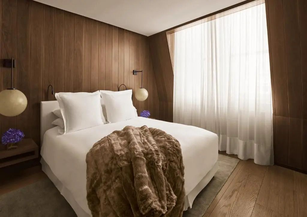 Modernes Deluxe Doppelzimmer im The London EDITION mit edlem Holz und großem Bett.