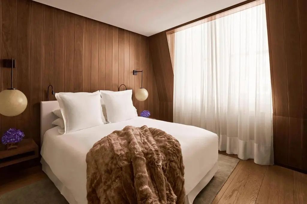 Stilvolles Schlafzimmer mit großen Fenstern und plüschigem Bettüberwurf
