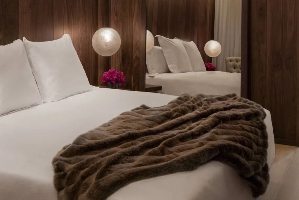 Luxuriöses Schlafzimmer mit weichen Stoffen und stilvollen Lampen im London EDITION Hotel.