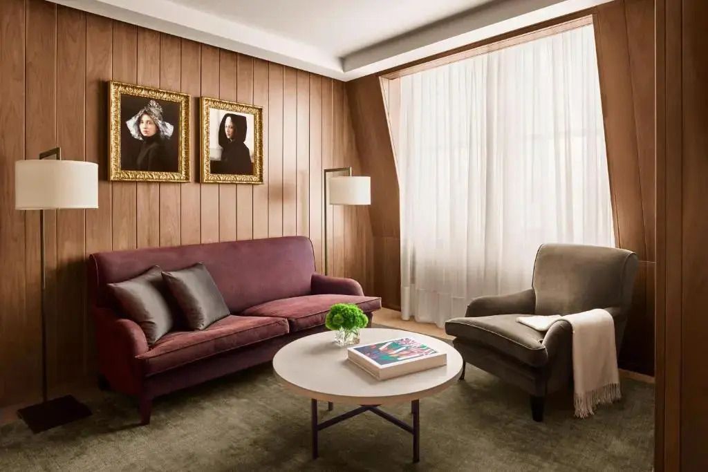 Eleganter Wohnbereich mit bequemer Couch, stylischem Sessel und Kunstwerken an holzgetäfelten Wänden