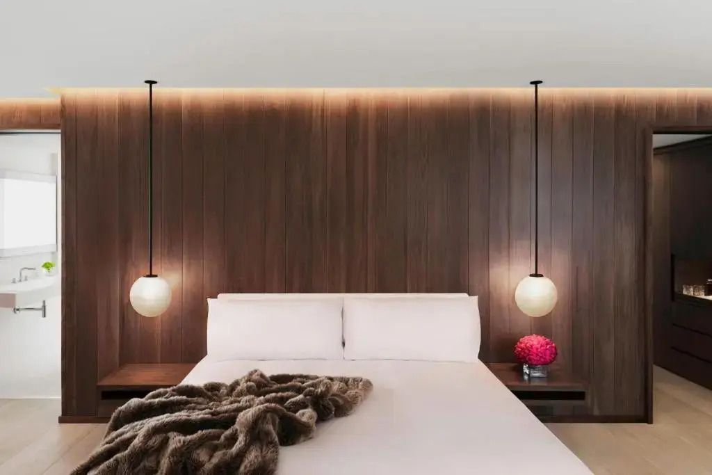 Luxuriöses Doppelbett mit Holzvertäfelung und stilvollen Hängelampen