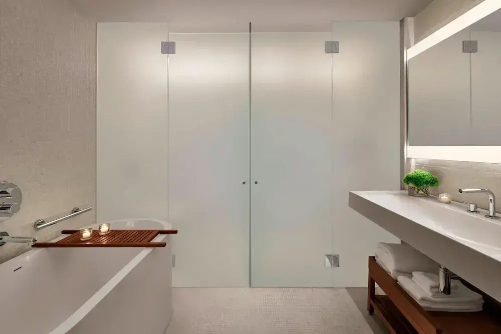 Modernes Badezimmer mit Glaswänden und Badewanne mit Kerzen