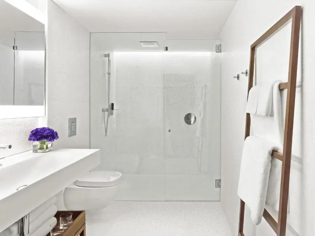 Modernes Badezimmer mit Duschkabine, weißem Interieur und dezenten Accessoires
