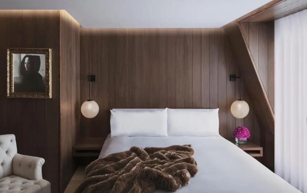 Gemütliches Doppelzimmer mit hölzerner Wandverkleidung und eleganter Beleuchtung.