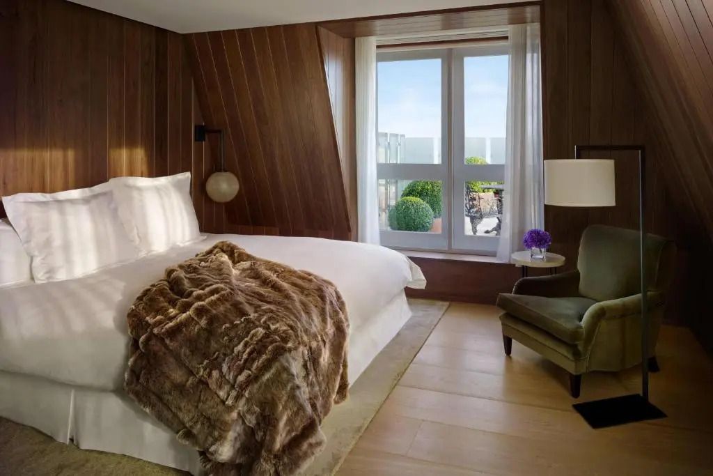Chices Schlafzimmer mit Holzwänden, großem Bett und Blick auf Terrasse