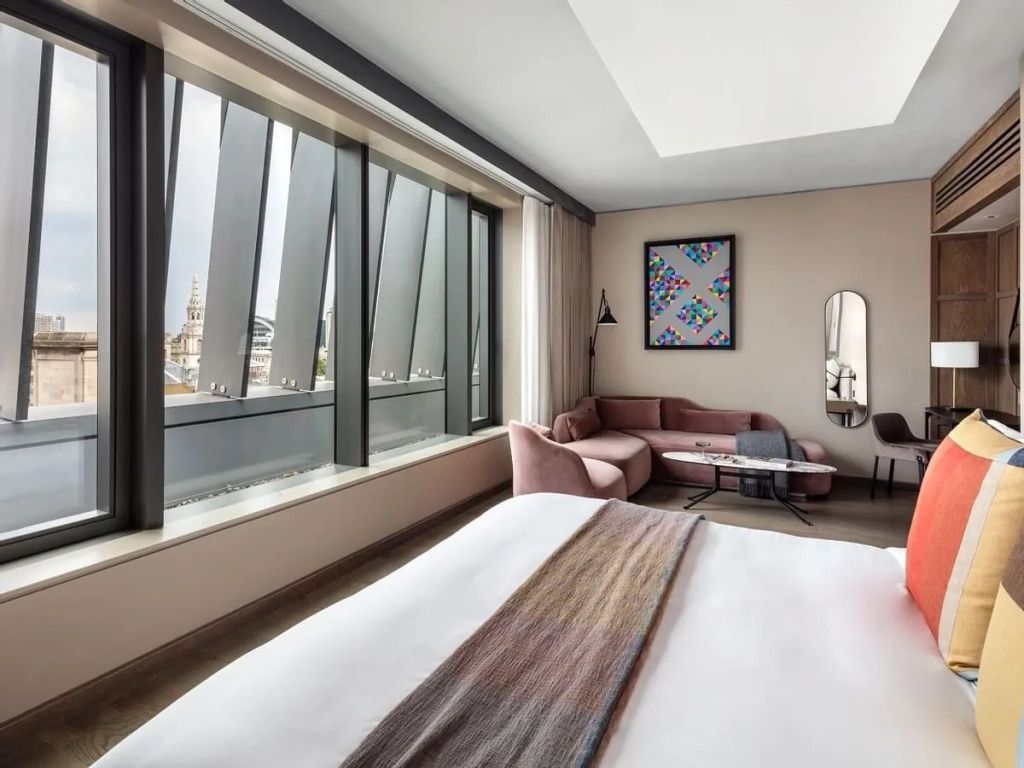 Luxuriöses Schlafzimmer mit gemütlicher Sitzecke und städtischem Ausblick