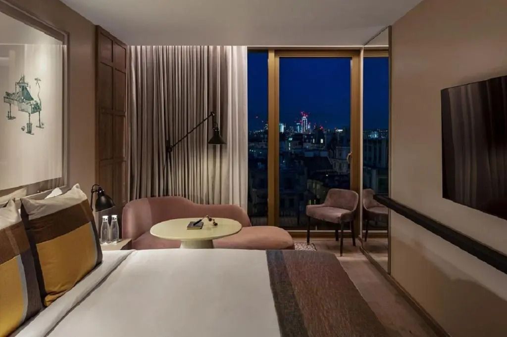 Hotelzimmer mit Doppelbett und Aussicht auf die nächtliche Skyline
