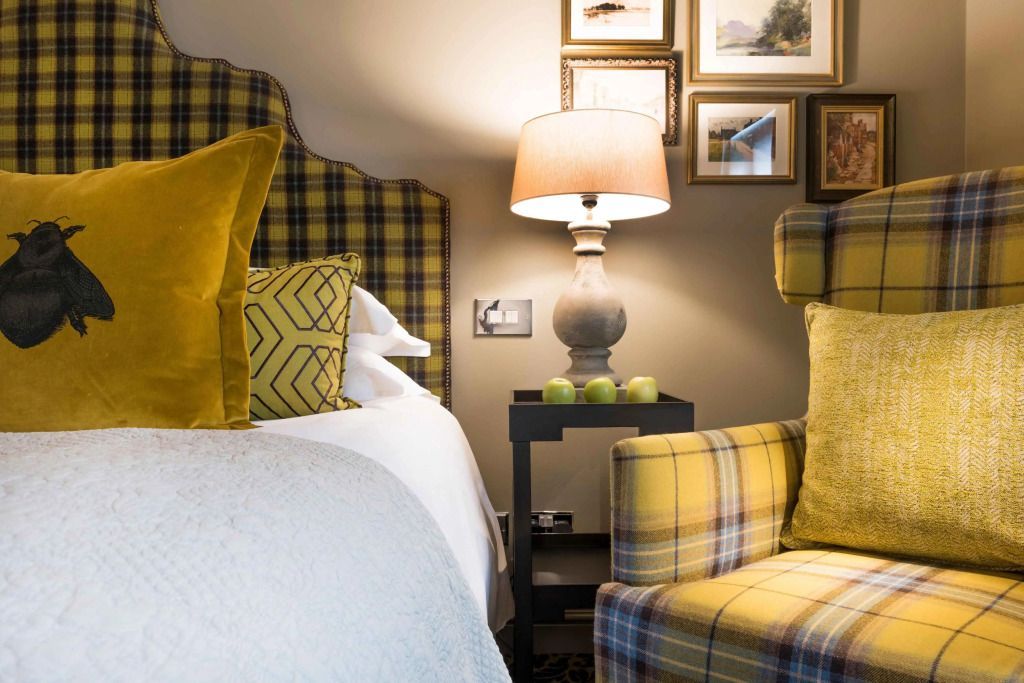 Gemütliches Hotelzimmer mit kariertem Sessel und kunstvoller Wanddekoration.