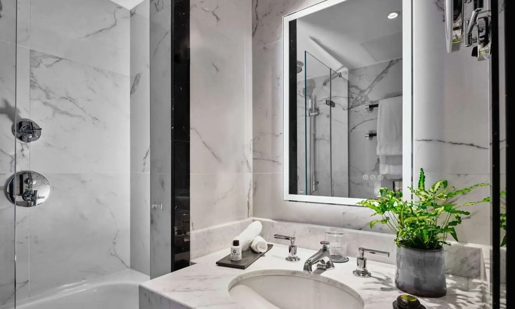 Modernes Badezimmer mit Marmorverkleidung und großzügigem Spiegel