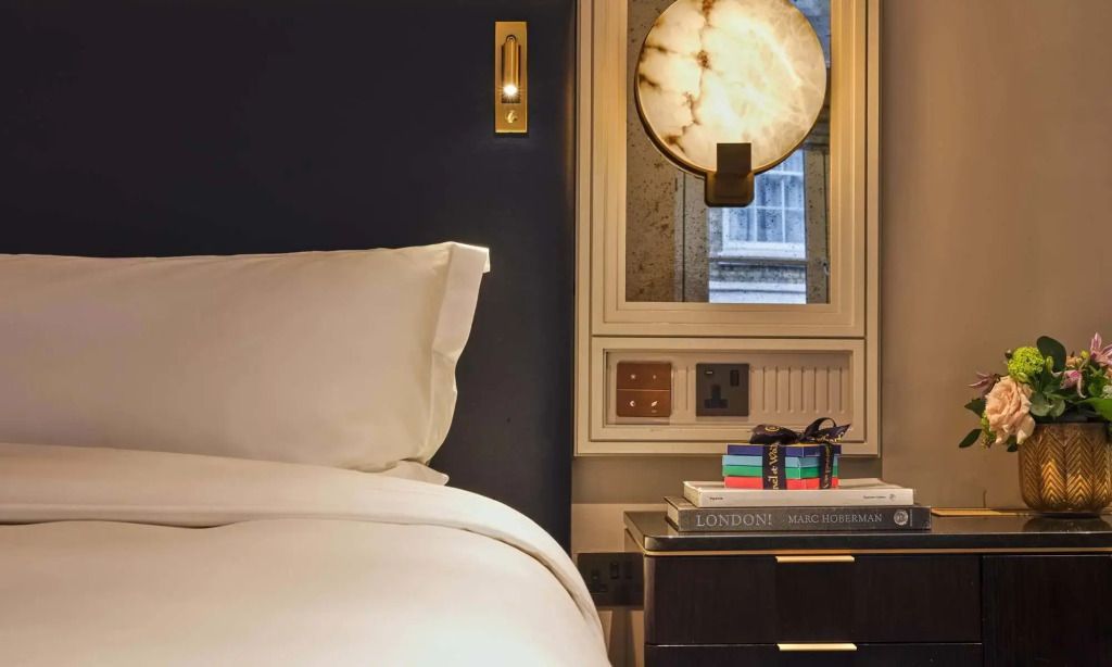 Detailansicht eines Nachttisches mit Designerlampe und stilvollen Accessoires.