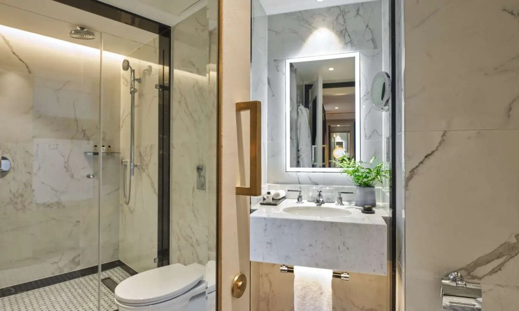 Modernes Badezimmer mit Mamorwaschbecken und beleuchtetem Spiegel.