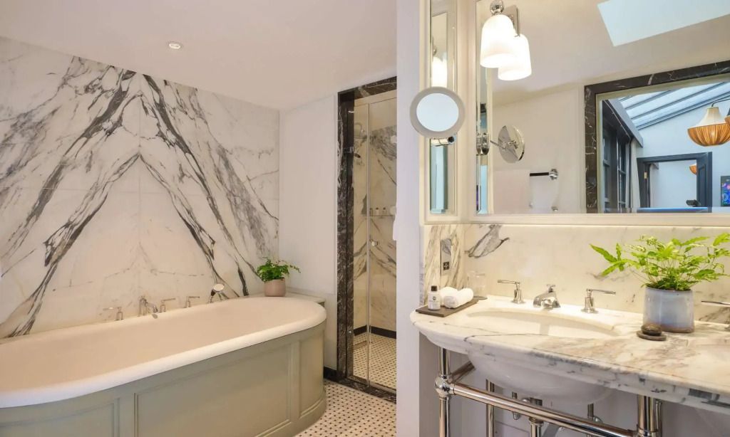 Marmorbadezimmer mit freistehender Badewanne und modernen Armaturen in der Suite