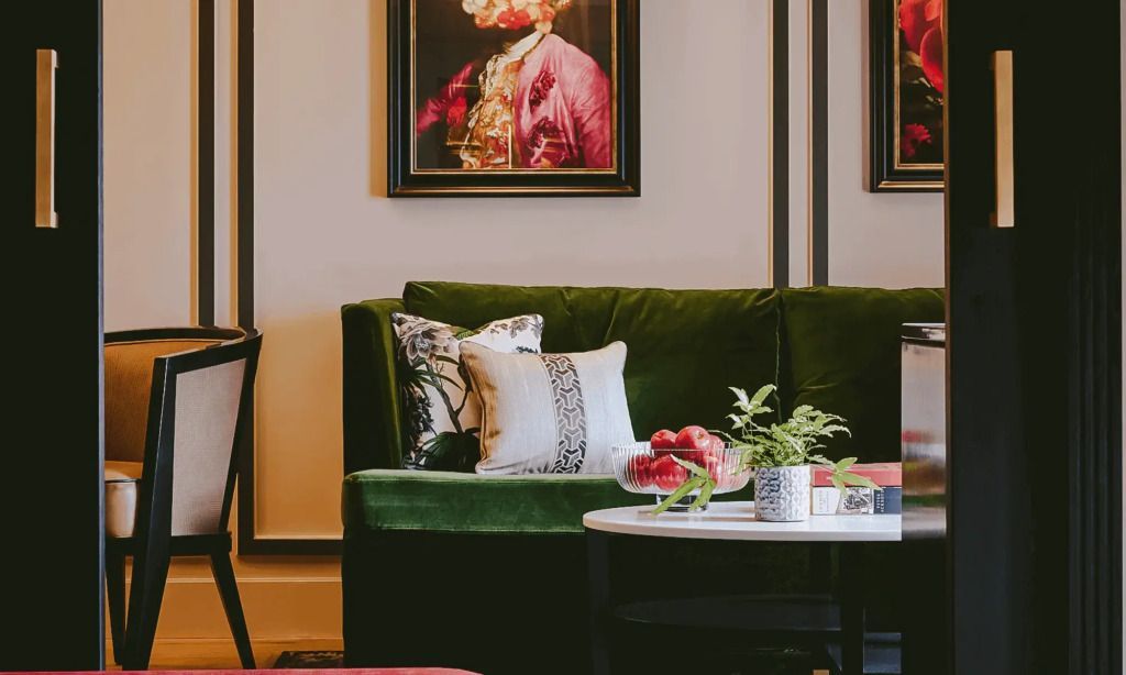 Grüne Couch mit stilvollen Kissen und einem Kunstbild an der Wand in der Suite