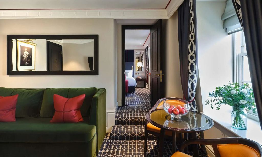 Suite mit grünem Sofa und Blick auf Schlafzimmer durch offene Tür