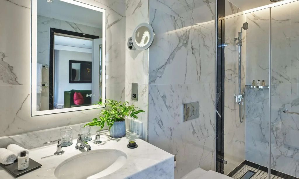 Modernes Badezimmer mit Marmorwänden und Pflanzenarrangement