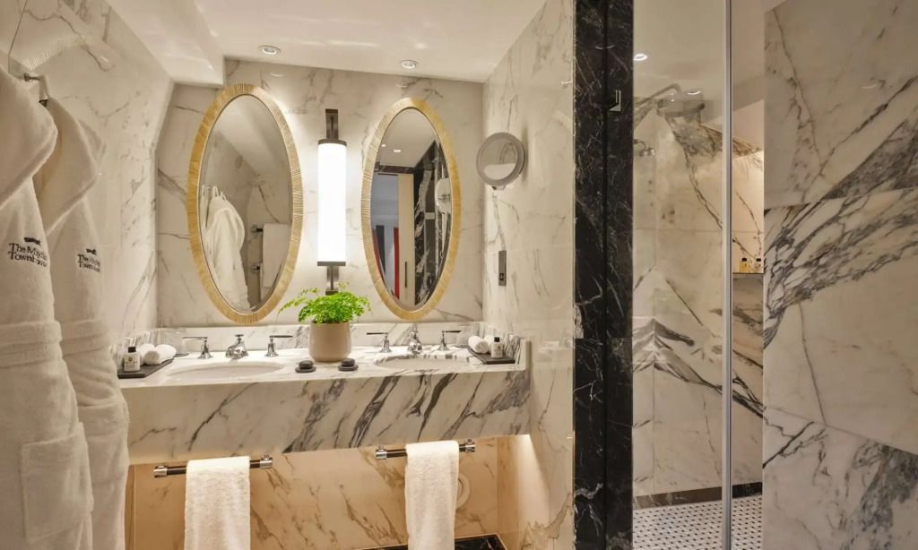 Modernes Badezimmer in Marmoroptik mit Doppelwaschbecken und runden Spiegeln