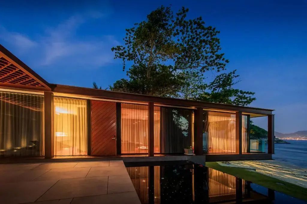Außenansicht der Villa bei Nacht mit warmem Licht und Pool