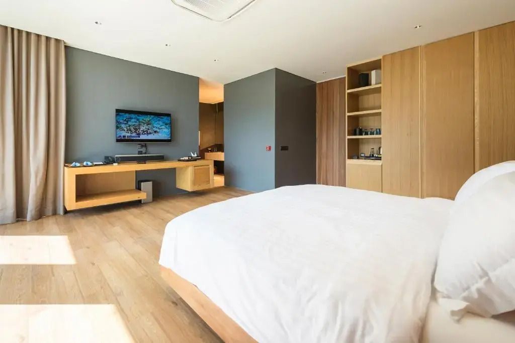 Großzügiges Schlafzimmer mit großem Bett, Wandregal und Blick in ein luxuriöses Badezimmer.