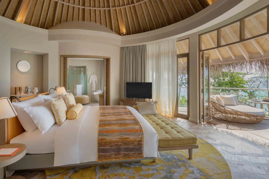 Luxuriöses Schlafzimmer mit Blick auf Terrasse und Garten. Große Fenster und Holzdach.