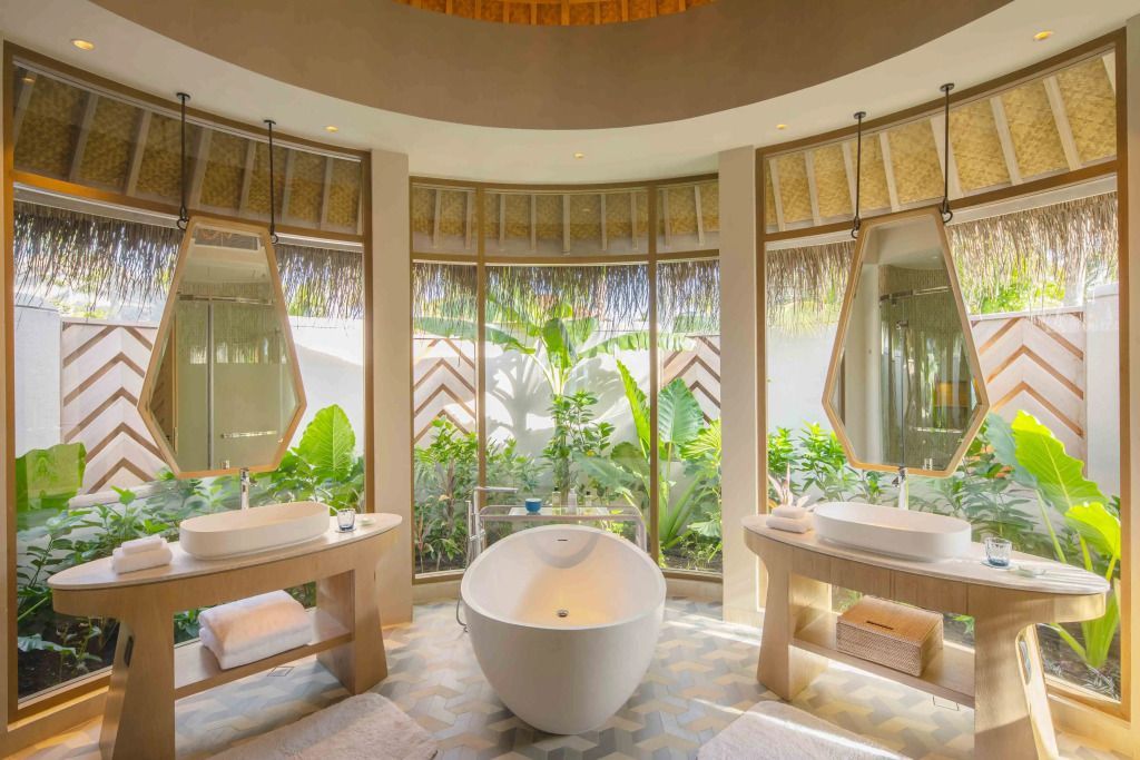 Modernes Badezimmer mit freistehender Badewanne und großen Fenstern in der Natur.