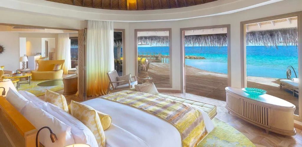 Offenes Schlafzimmer mit Blick auf einen privaten Holzterrasse und das Meer.