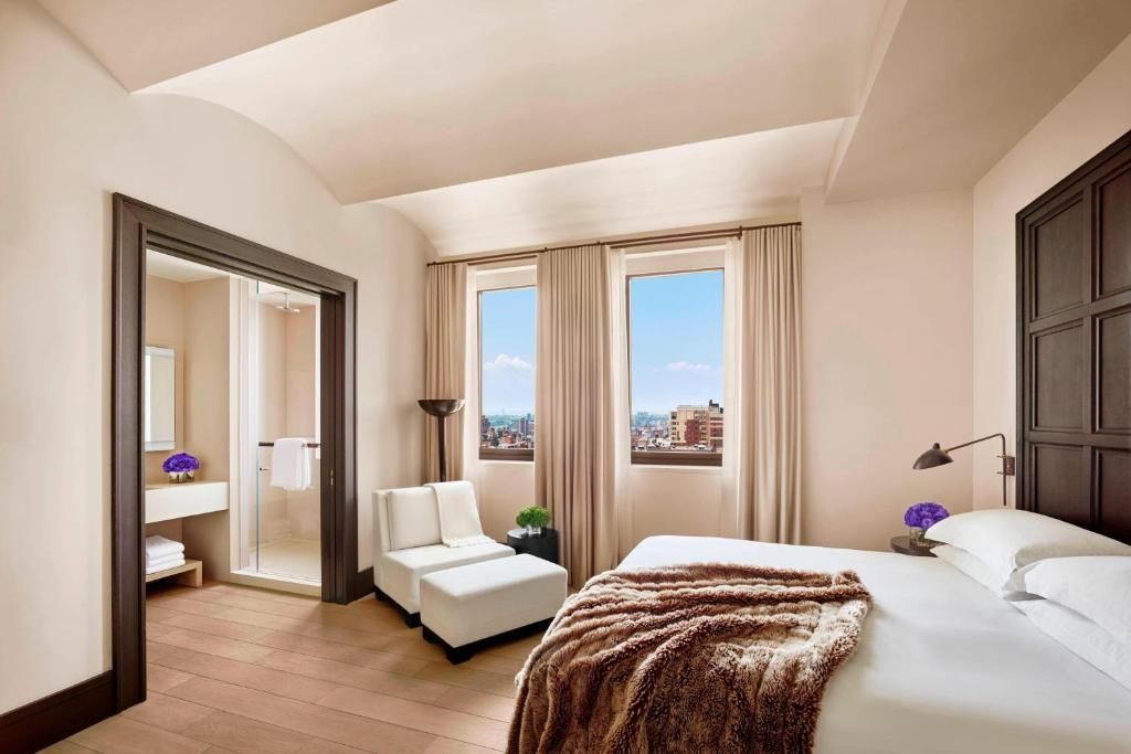 Helles Schlafzimmer mit Doppelbett und Stadtblick in eleganter Suite