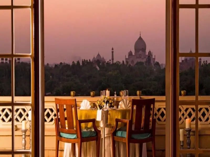 Blick von einer Terrasse auf das Taj Mahal bei Sonnenuntergang mit gedecktem Tisch