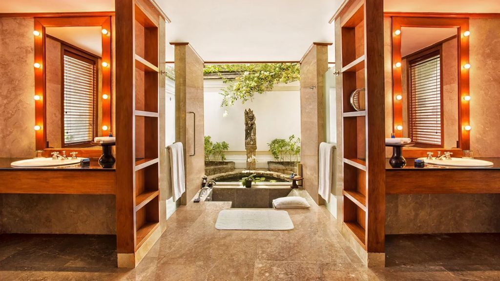 Offenes Badezimmer mit Naturstein und Innenhof mit Wasserblick und Pflanzen.