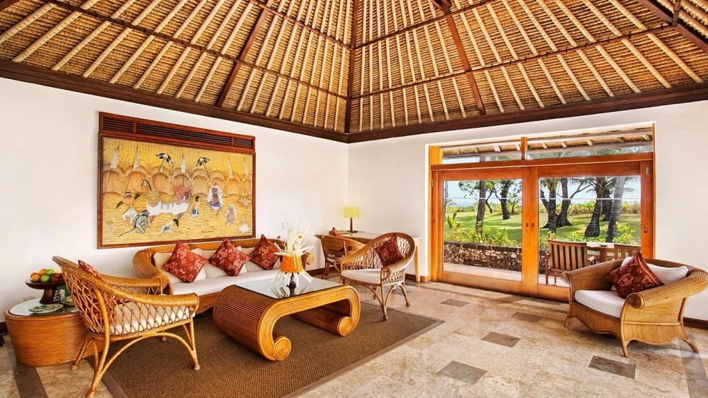 Luxuriöser Wohnbereich mit Rattanmöbeln und kunstvoller Wanddekoration