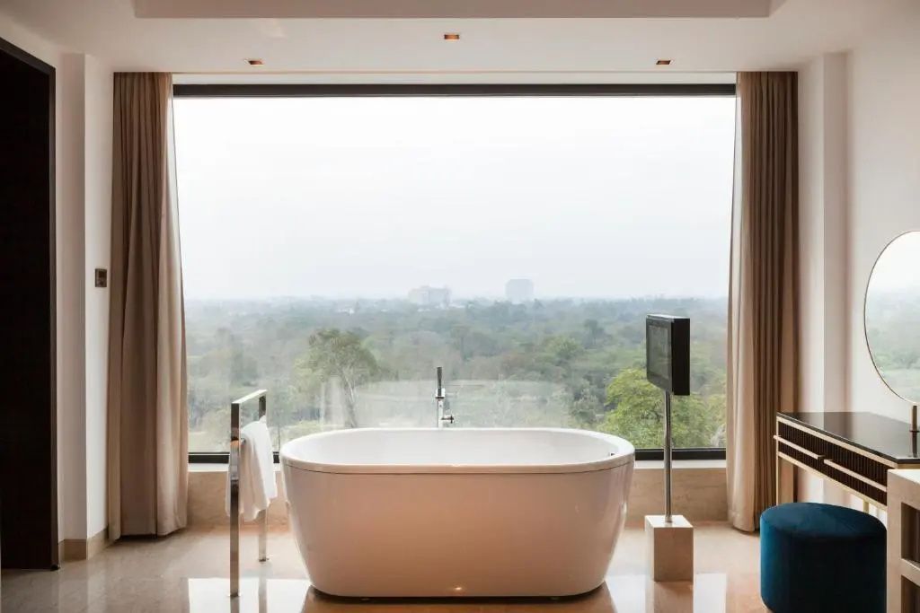 Freistehende Badewanne mit spektakulärem Ausblick auf die grüne Landschaft von New Delhi.